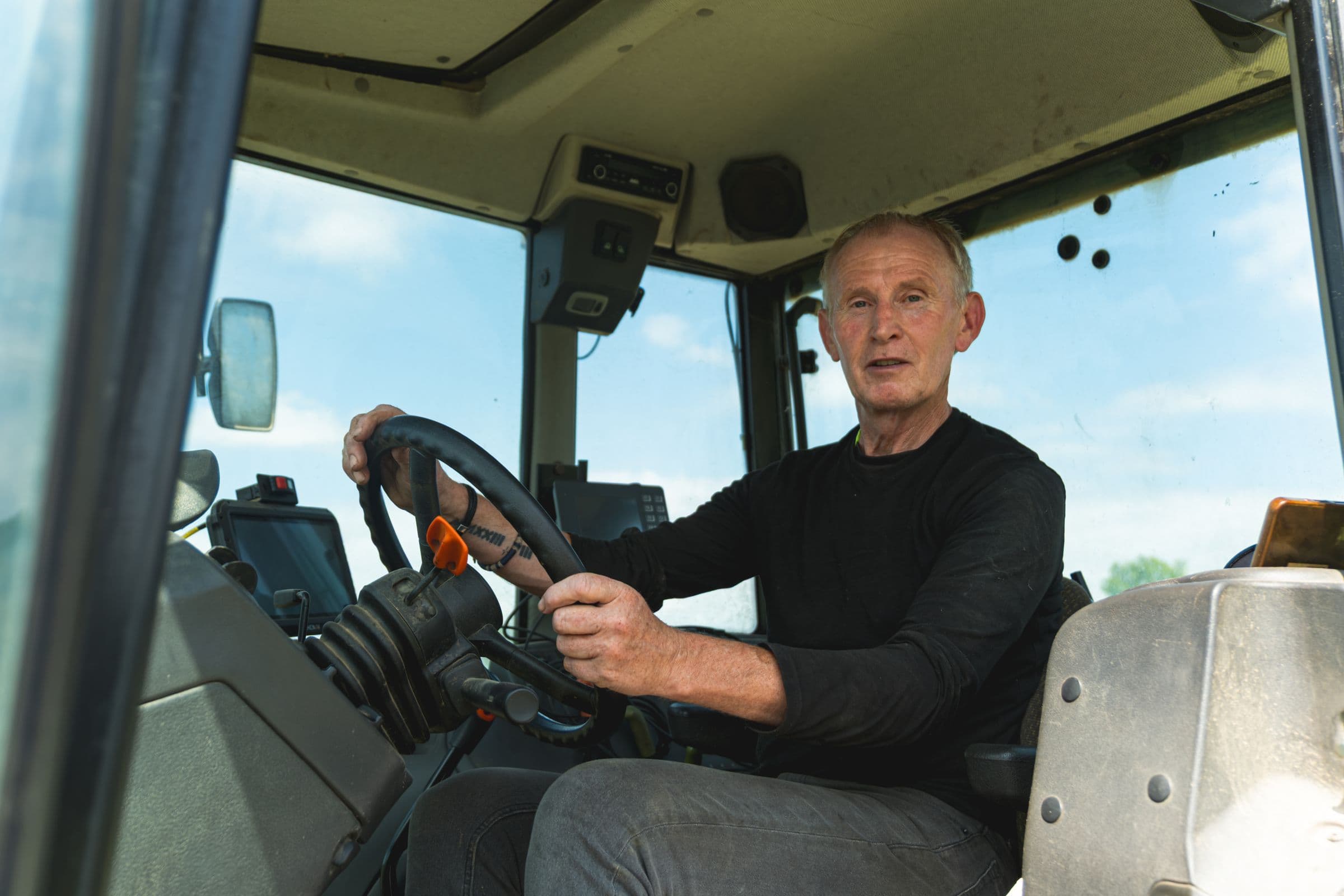 Ouvrier agricole au volant d’un tracteur, vu depuis la portière de la cabine